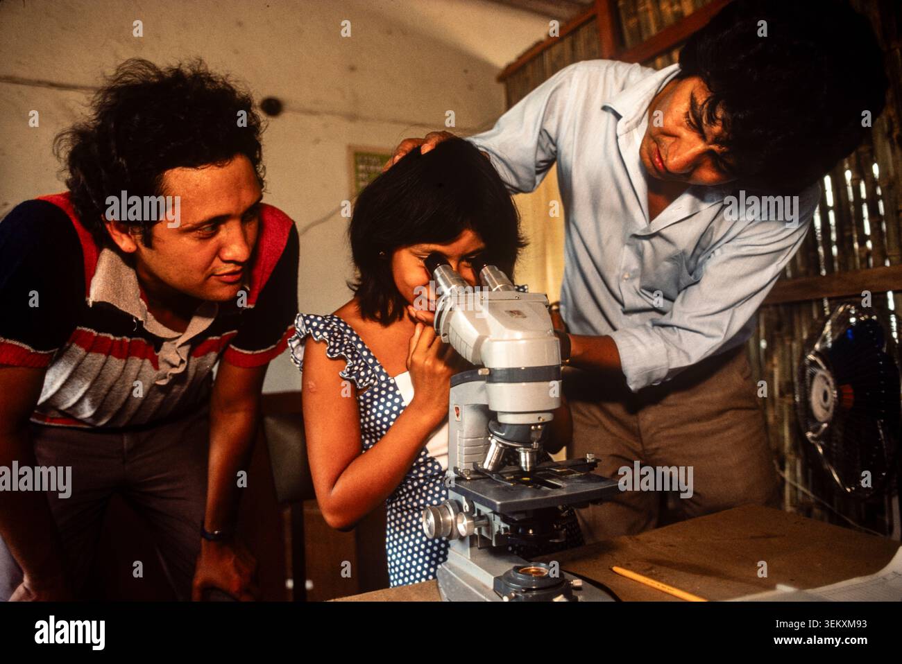 Einer Frau wird geholfen, zum ersten Mal durch ein Mikroskop in einer medizinischen Klinik in Veracruz, Mexiko, zu schauen. 1993 g Stockfoto
