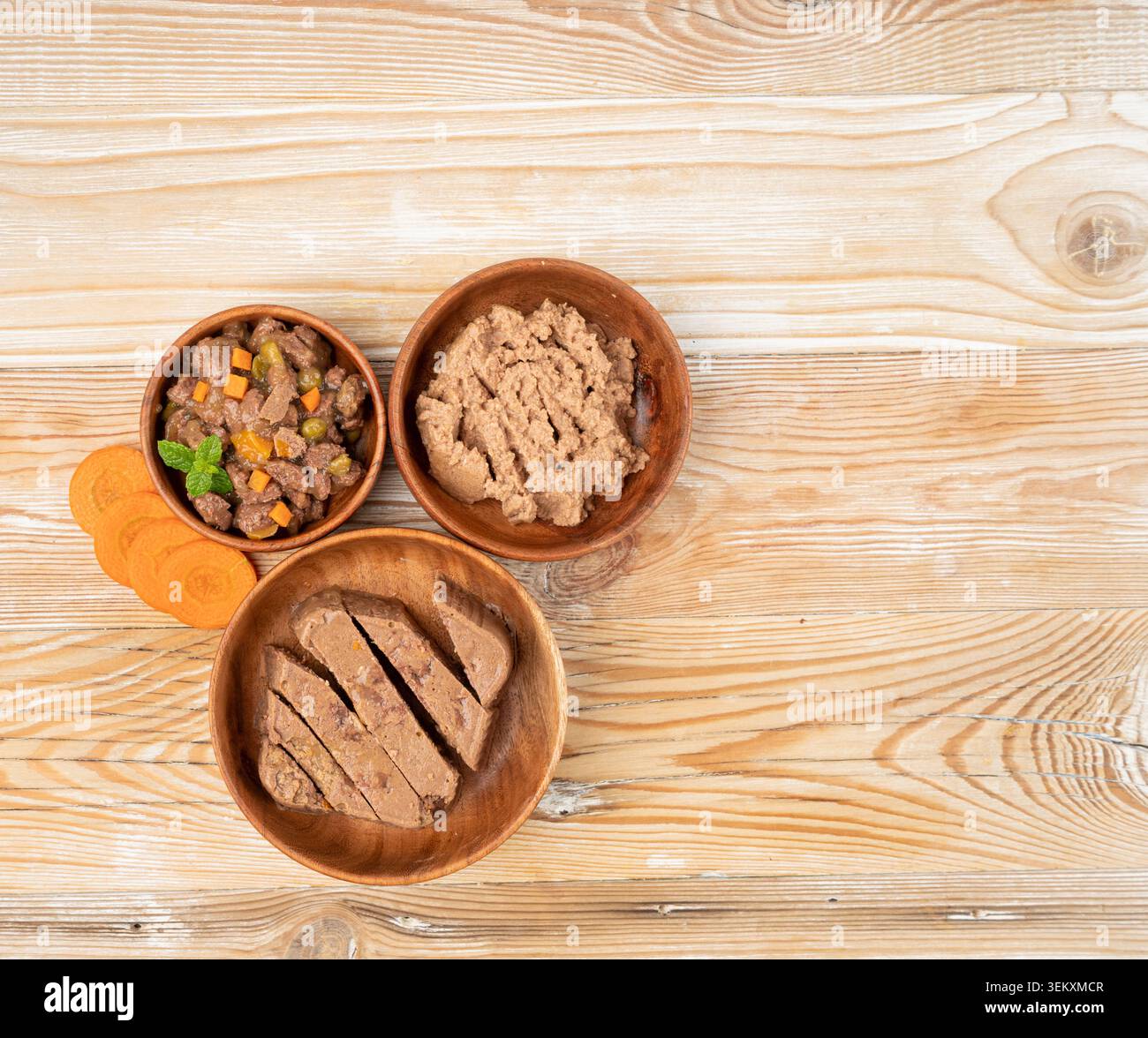 Haustierfutter auf Holzfußboden Hintergrund, Nassfutter für Katzen in der Holzschüssel mit Karotten, Dog Dog Pate, weiches Haustierfutter auf weißem Hintergrund Stockfoto
