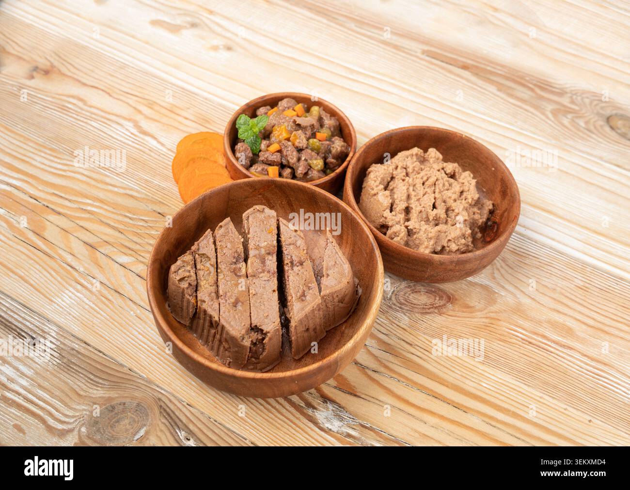 Haustierfutter auf Holzfußboden Hintergrund, Nassfutter für Katzen in der Holzschüssel mit Karotten, Dog Dog Pate, weiches Haustierfutter auf weißem Hintergrund Stockfoto