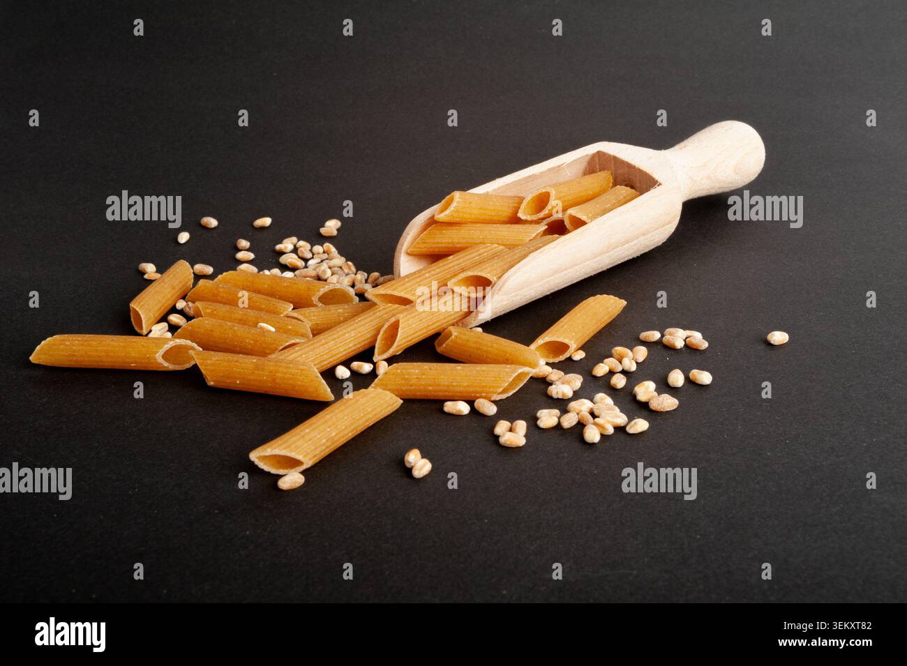 Rohe braune Nudeln, Vollkorn-Penne-Stapel in Scoop, trockene Vollkornnudeln, rohe Dinkel-Makkaroni, gesunde italienische Lebensmittel, Bio-Mahlzeit, Weizen-Pasta auf Bla Stockfoto