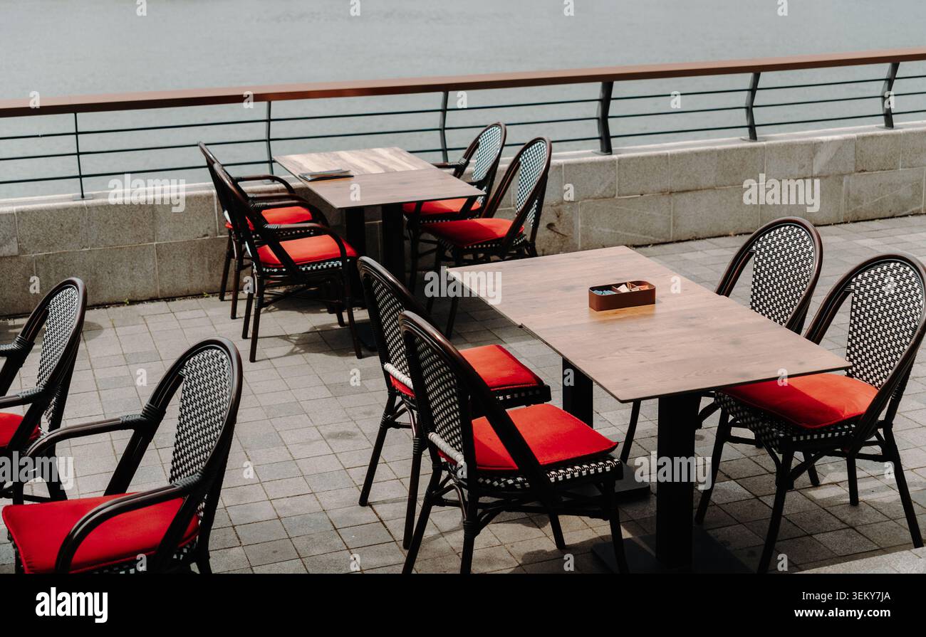 Essbereich im Freien mit Blick auf eine Uferpromenade. Gastfreundschaft und Tourismuskonzept. Stockfoto