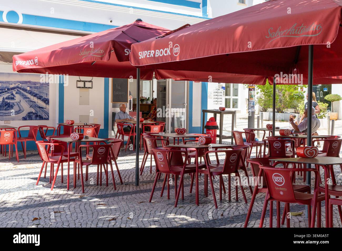 Lagoa Algarve Portugal, Ein bezauberndes Café im Freien mit roten Tischen und Stühlen, im Schatten großer Sonnenschirme, lädt Gäste zum Entspannen und Genießen des Tages ein Stockfoto