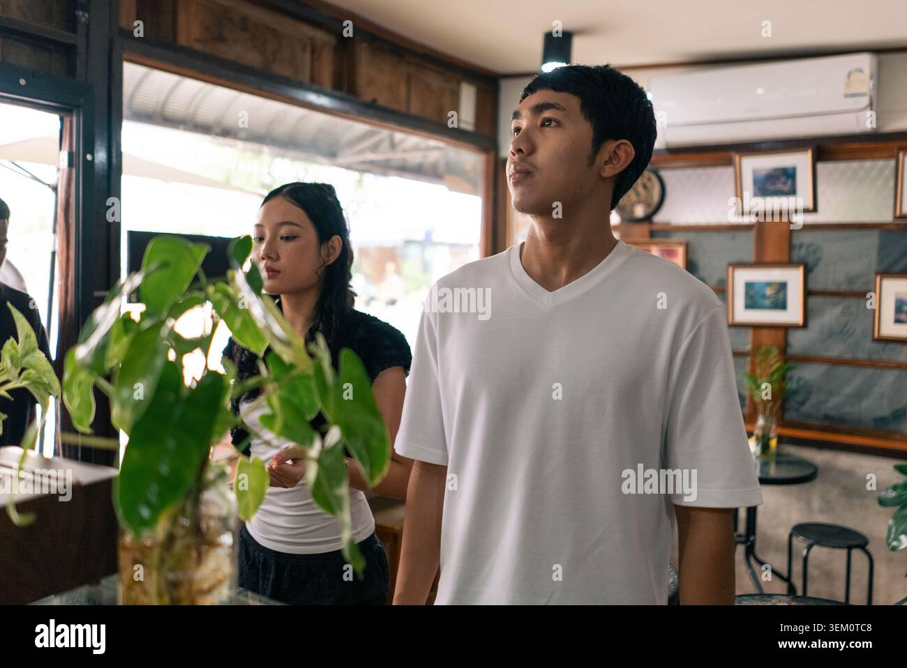 Junger Mann in einem weißen T-Shirt, der neugierig in einem Café schaut Stockfoto