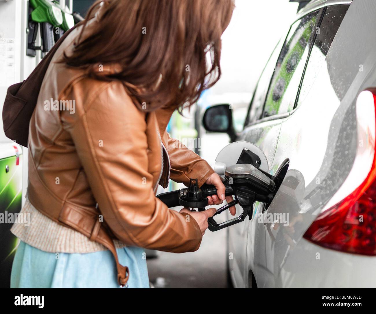Eine Frau füllt das Auto mit Benzin an Einer Tankstelle mit Einer Kraftstoffpumpe Stockfoto