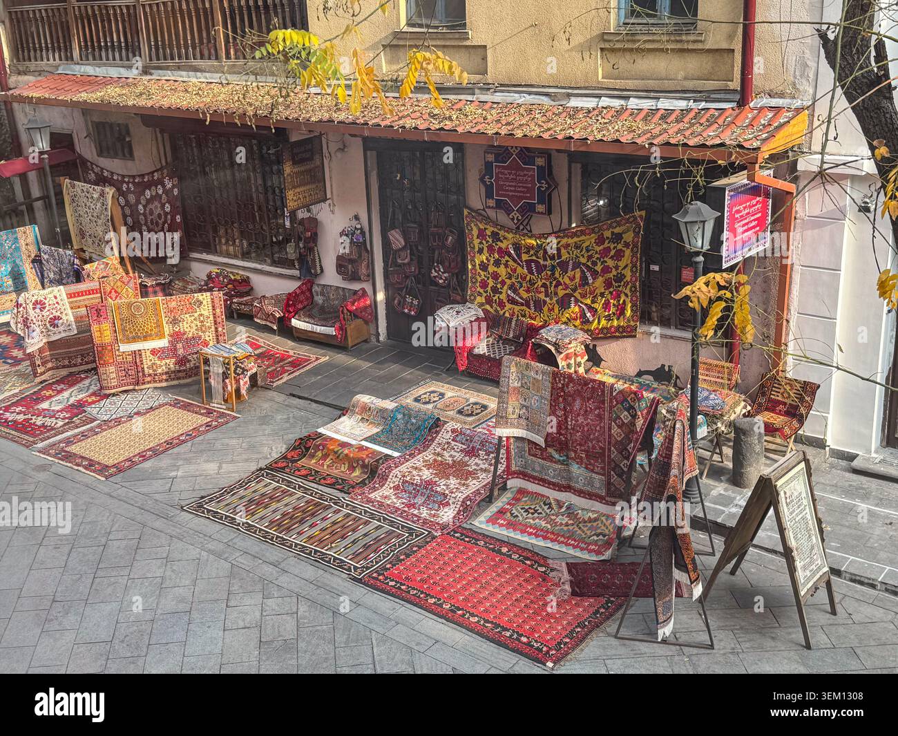 Traditionelles Teppich- und Textilgeschäft mit handgefertigten Teppichen und dekorativen Stoffen in Old Tiflis, Georgia. - Smartphone-aufgenommenes Stockfoto