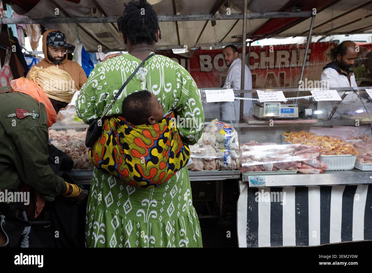 Einkäufer in einem Geflügelstand auf dem Barbès-Rochechouart-Markt in Paris, Frankreich. Stockfoto