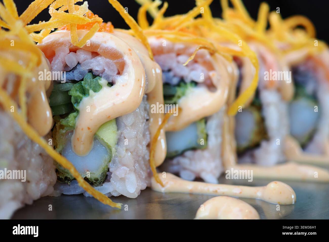 Sushi-Brötchen mit Sauce und Belägen auf einem Teller Stockfoto