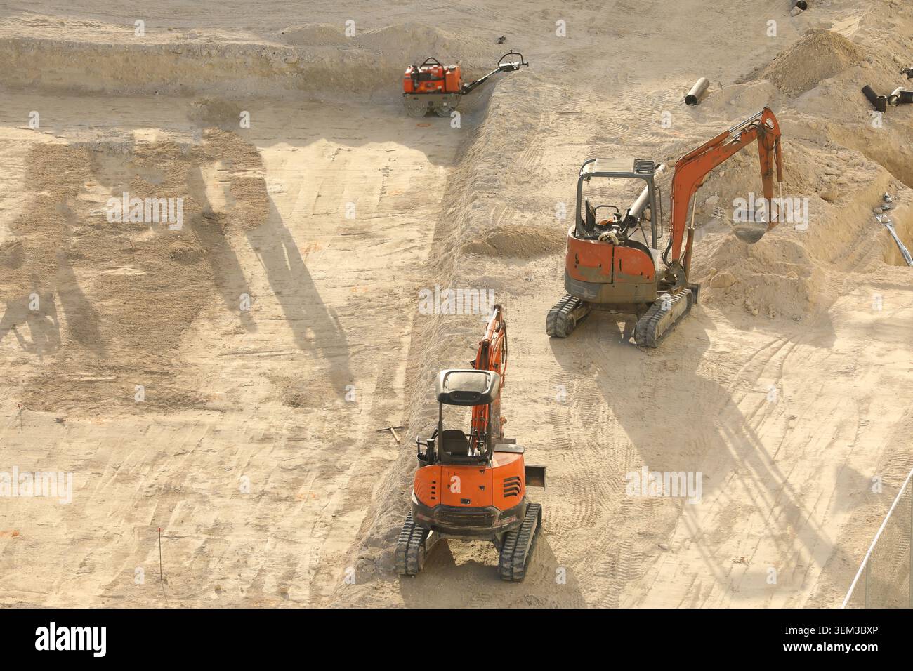 Orange Doosan Minibagger mit kompakter Raupenkette, die auf einer Sandbaustelle arbeiten und den Boden für Fundamente vorbereiten. Stockfoto