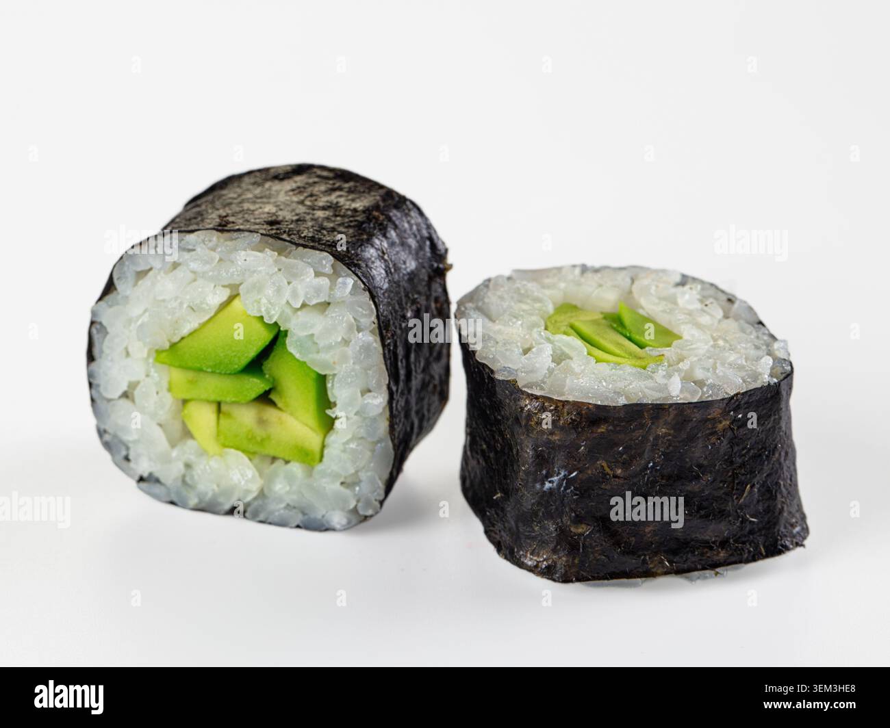 Nahaufnahme von zwei frischen Avocado-Maki-Sushi-Rollen isoliert auf weißem Hintergrund. Minimalistisches Studio mit hellen Lichtern in Grün, weiß und blau Stockfoto
