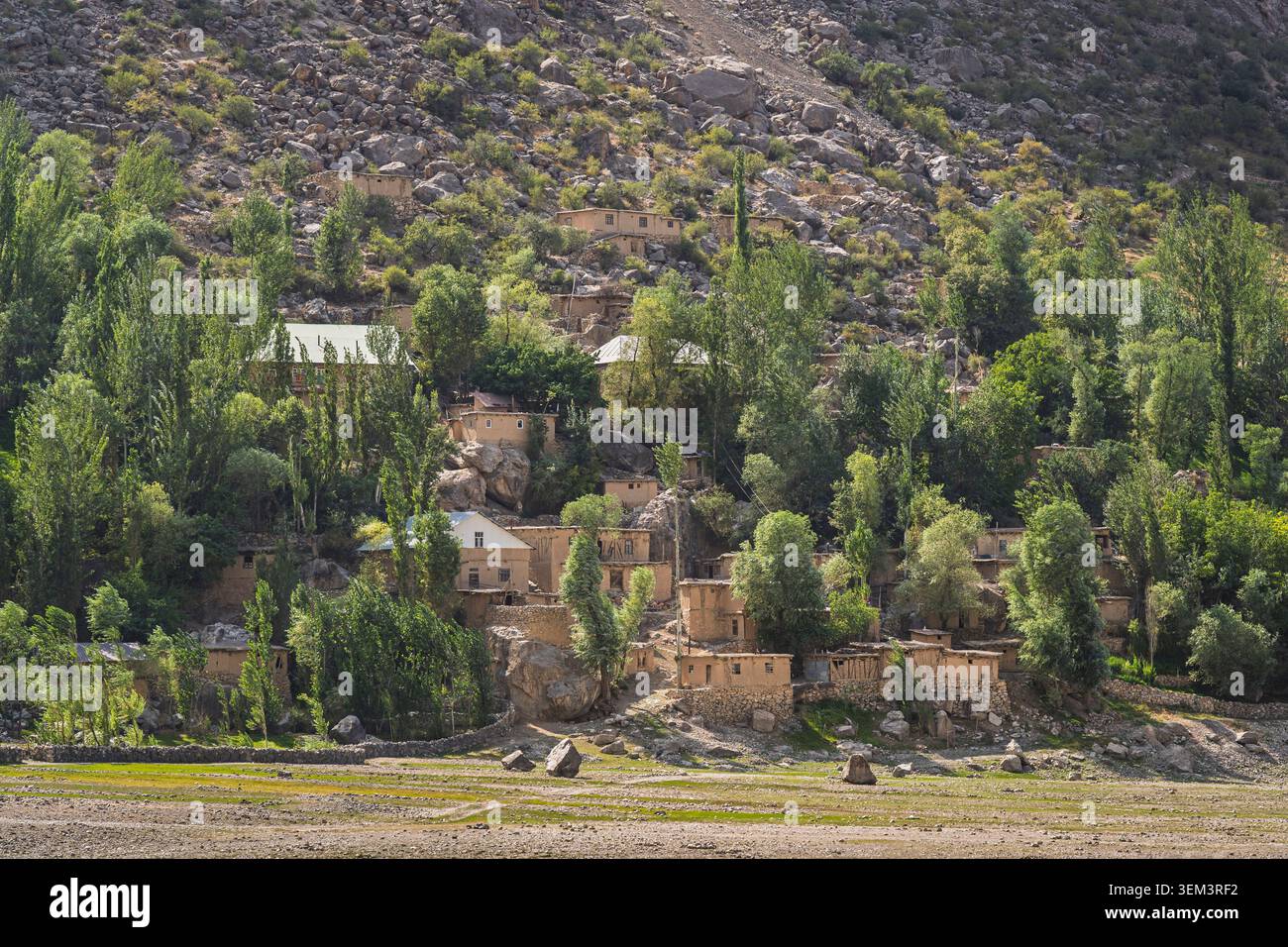 Malerischer Blick auf das traditionelle ländliche Dorf zwischen Bäumen am Ufer des Marguzor Sees am späten Nachmittag, Haft Kul, Sughd, Tadschikistan Stockfoto