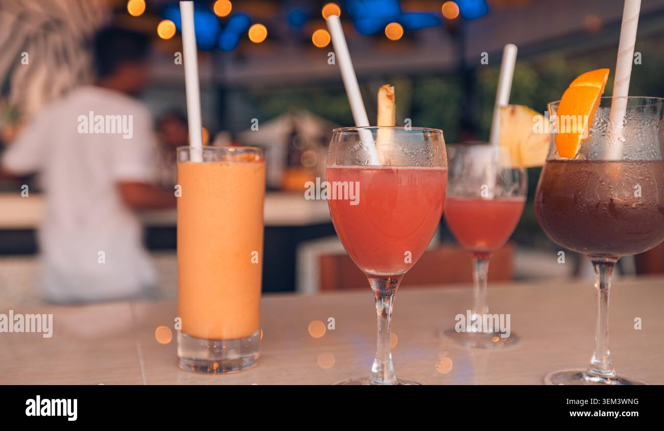 Erfrischende Sommercocktails auf der Theke einer tropischen Strandbar mit verschwommenen Abendlichtern. Getränkeurlaub Nachtleben Party. Urlaubsreise Resort exotisch Stockfoto