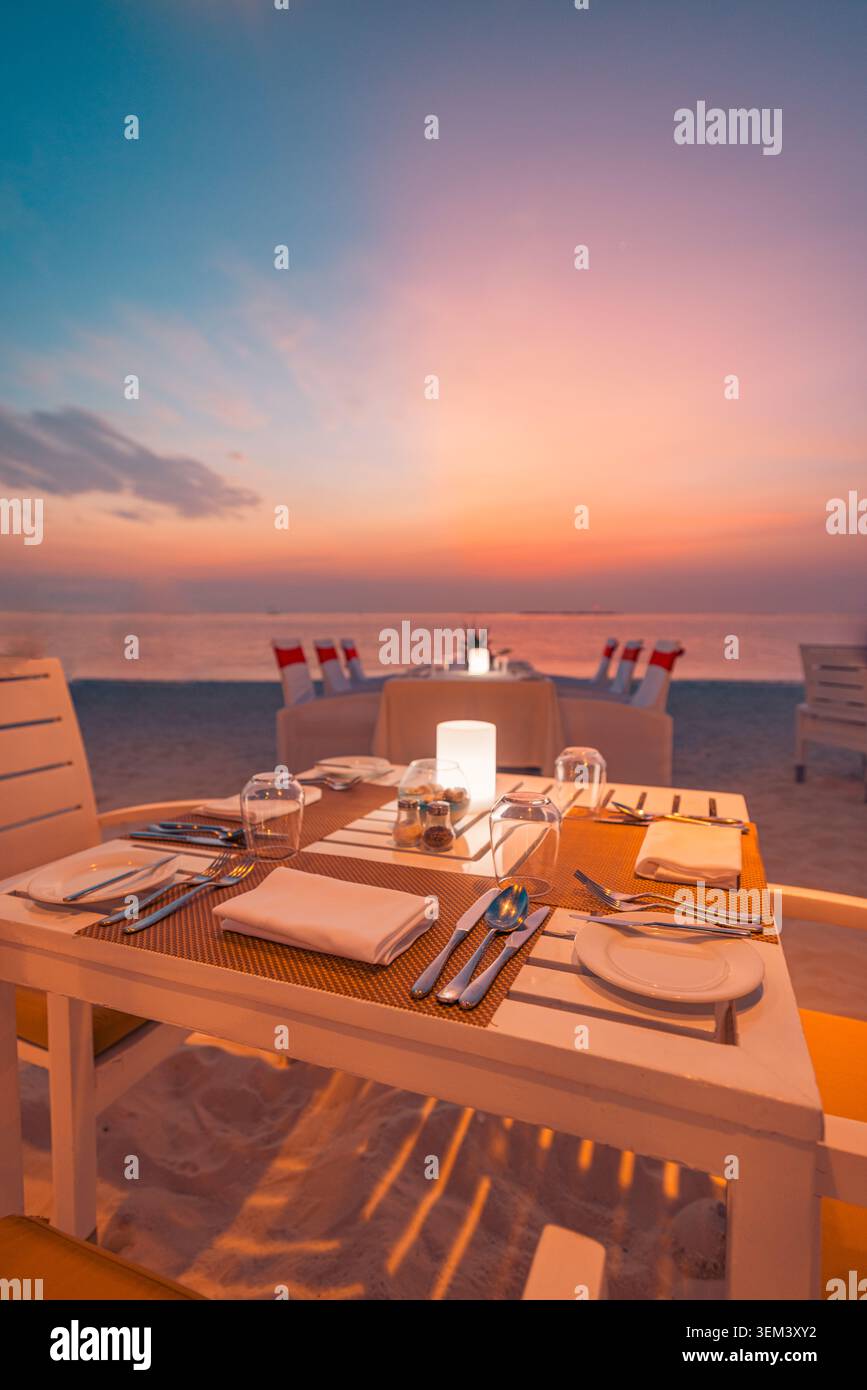 Privater Kerzenlicht-Strandabendtisch für zwei bei tropischem Sonnenuntergang am Meer. Rosa Himmel Paar Flitterwochen Romantik. Sommerreisen Urlaub Ferienausflug Stockfoto