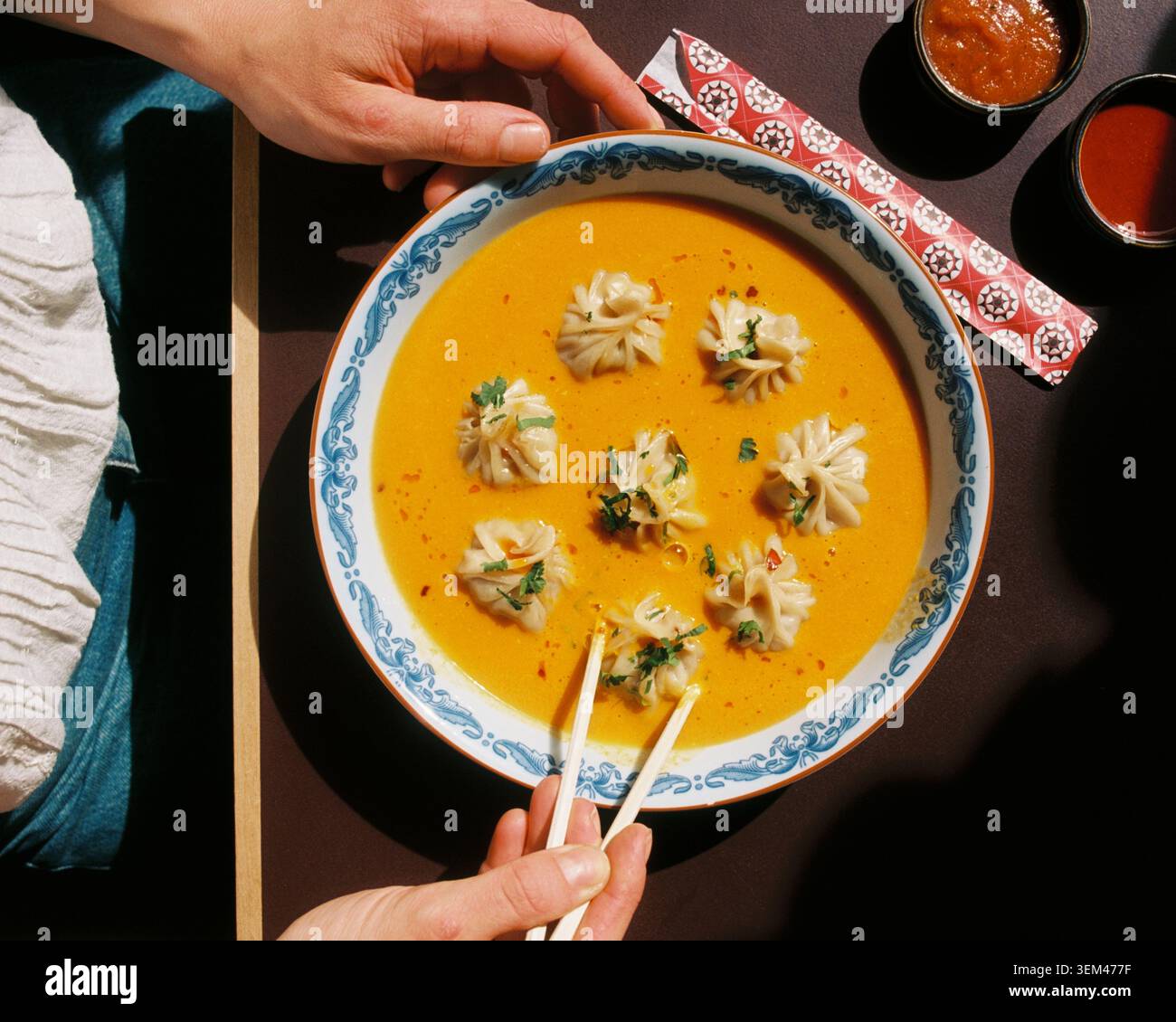 Eine Person isst Teigtaschen in Suppe aus einer Schüssel in einem Himalaya-Restaurant Stockfoto