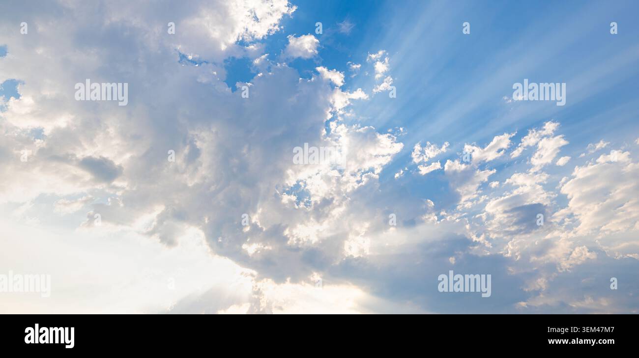 Sonnenlichtstrahlen, die durch weiße Wolken über weiten blauen Himmel am Tag streifen. Helle Sonnenstrahlen-Wolkenlandschaft. Himmel Wolken Natur Himmel Kopierraum Stockfoto