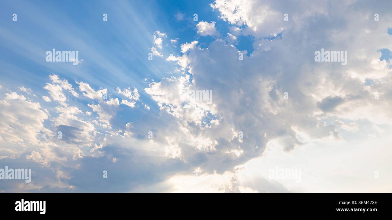 Helle Sonnenstrahlen, die durch dramatische weiße Wolken im blauen Himmel scheinen. Sonnenstrahlen, Gottesstrahlen, Wolkenhimmel. Himmel, Wolken, Naturhintergrund, Himmel, Kopierraum, sonnig Stockfoto