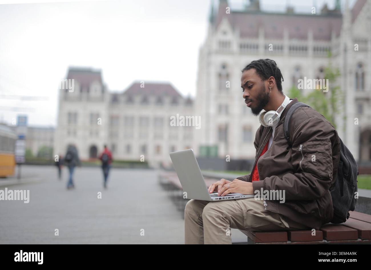 Ein fokussierter junger Mann arbeitet an einem Laptop auf einem Stadtplatz Stockfoto