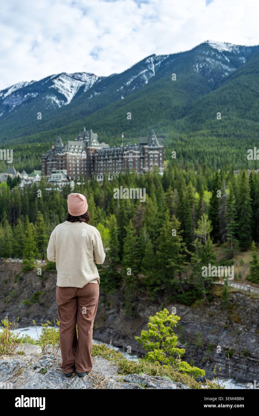 Frau, die das berühmte Hotel und die Berge im Banff National Park ansieht Stockfoto