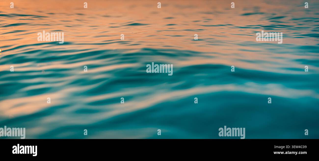 Die Oberfläche des Teal-Ozeans wölbt ein weiches Nachmittagslicht. Sanft rollende Wellen beruhigen die flüssige Textur. Ruhige, blau-grüne Oberfläche für eine beruhigende natürliche Kulisse Stockfoto