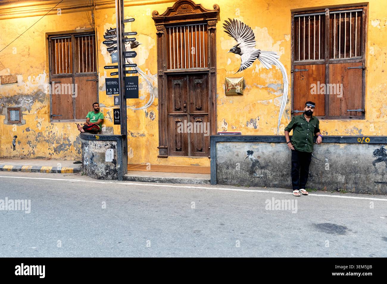 Täglich lebhafte Szenen aus dem Viertel Mattancherry in Kochi in Kerala, Indien, mit einheimischen Männern, die vor einem alten Kolonialgebäude sitzen und stehen Stockfoto