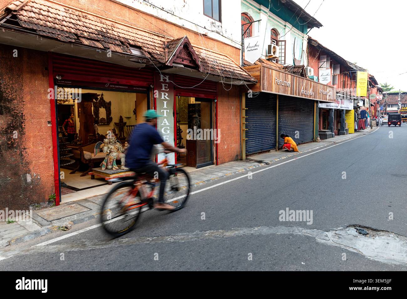 Täglich lebhafte Szenen aus dem Viertel Mattancherry in Kochi in Kerala, Indien, Radfahrer vorbei an Kunsthandwerksläden und Antiquitäten verkaufen Stockfoto