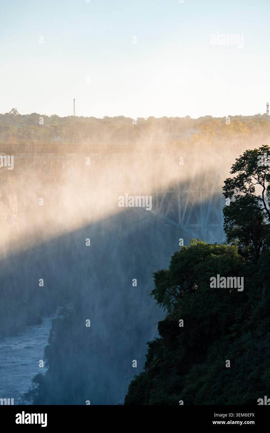 Victoria Falls bei Sonnenuntergang mit Victoria Falls Bridge im Nebel Stockfoto