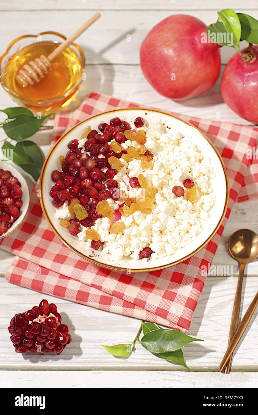 Körniger frischer Hüttenkäse mit Granatapfelsamen, Rosinen, Honig und Saft auf einem sonnigen Tisch, Entgiftungsdiät und natürliches Ernährungskonzept, gesundes LIFE Stockfoto