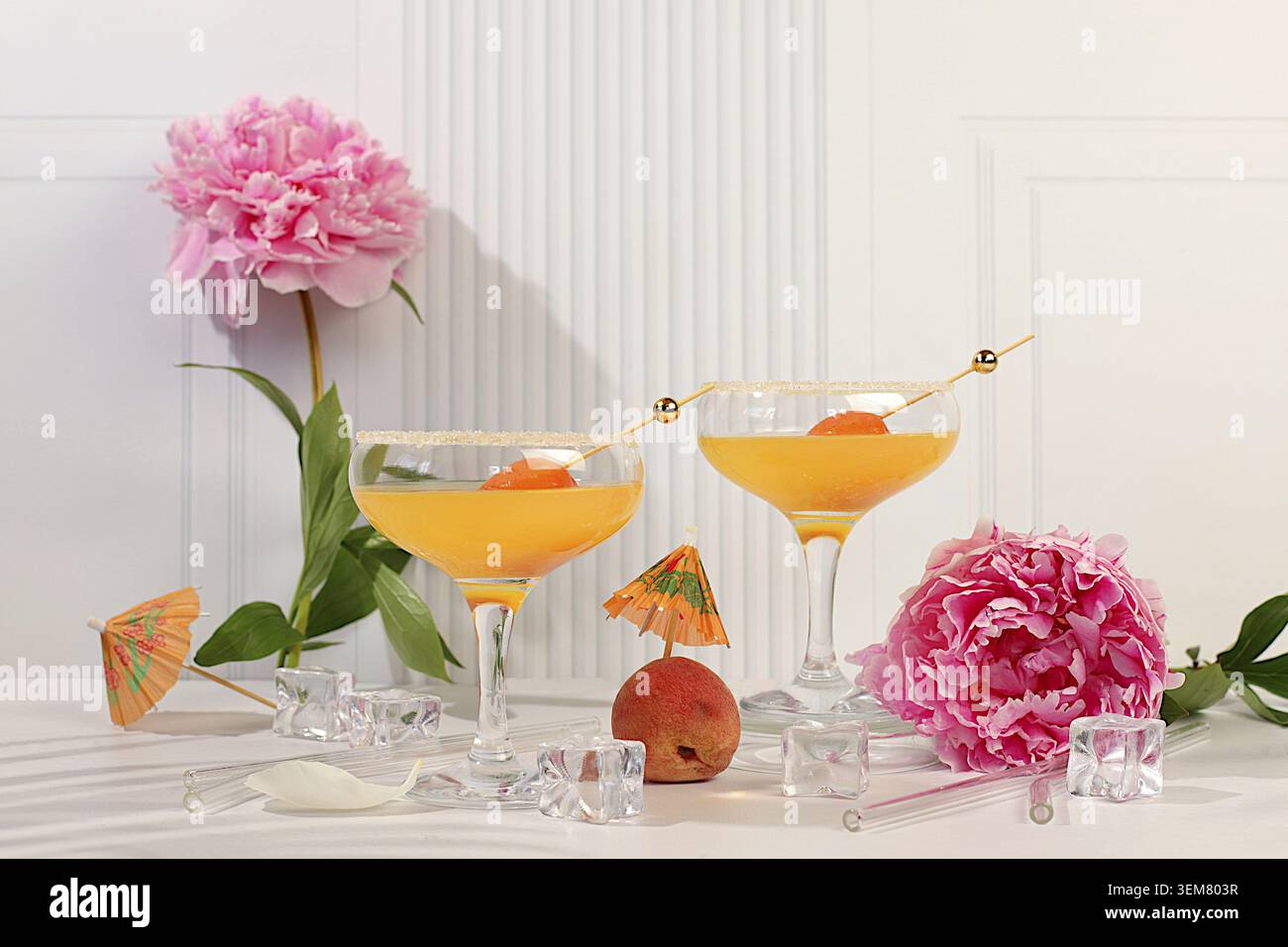 Modernes Stillleben mit Eispunsch mit Aprikosen, alkoholischem Sommercocktail für Partys und Pfingstrosen auf modernem sonnigem Hintergrund, minimalistisches Konzept für die Bar Stockfoto