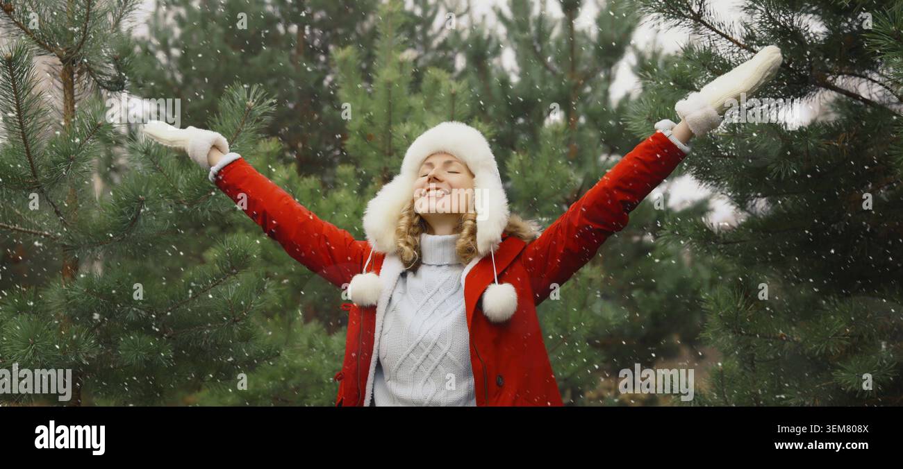 Wintertag, glueckliche laechelnde junge Frau geniesst Schnee, warmes Wetter gegen Weihnachtsbaum Stockfoto