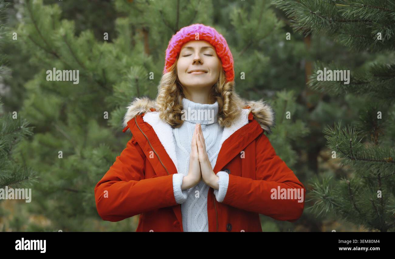 Ruhig entspannte gesunde Frau meditiert im Winterwald, Maedchen uebt Yoga-Uebungen im Freien Stockfoto