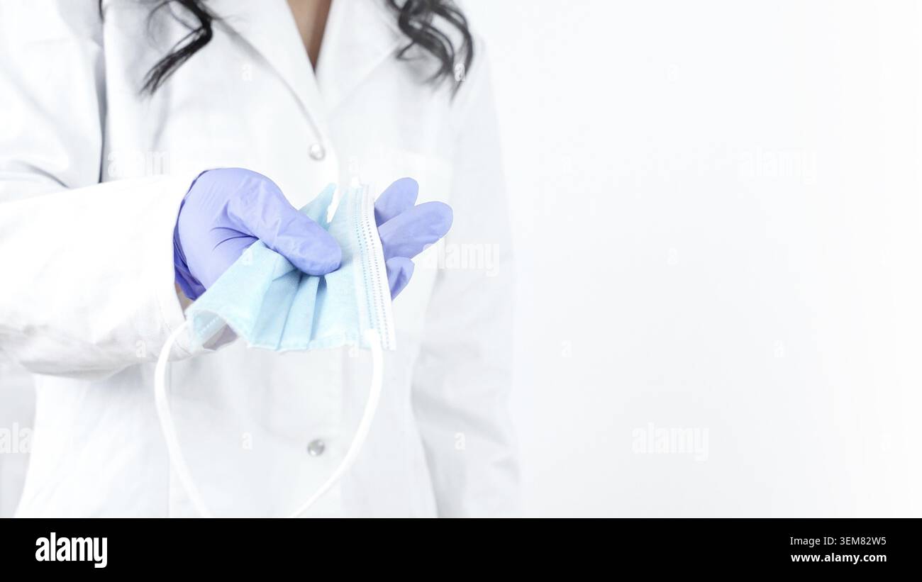 Nahaufnahme der Ärztehand, die eine medizinische Gesichtsmaske hält, auf weißem Hintergrund Stockfoto