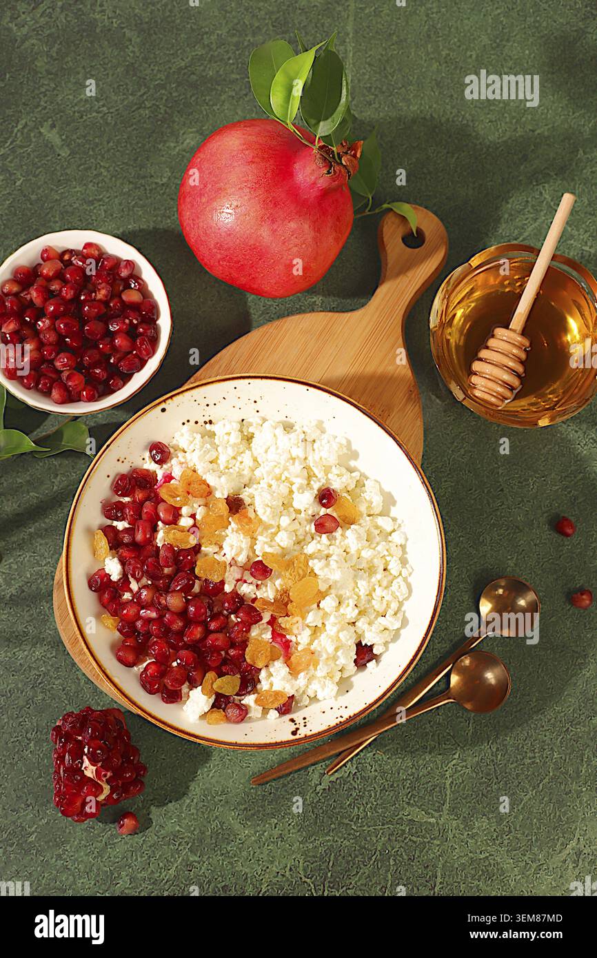 Körniger frischer Hüttenkäse mit Granatapfelsamen, Rosinen, Honig und Saft auf einem sonnigen Tisch, Entgiftungsdiät und natürliches Ernährungskonzept, gesundes LIFE Stockfoto