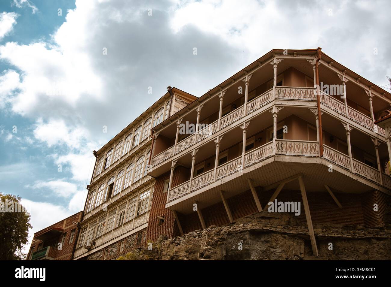 Historisches mehrstöckiges Haus mit geschnitzten Holzbalkonen, dekorativen Veranden und klassischen architektonischen Details auf einem felsigen Hügel. Landschaftlich Reizvoll Stockfoto
