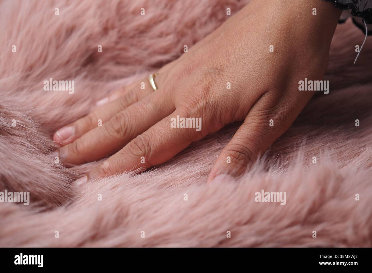 Die Hand berührt weiches rosafarbenes Material auf einer gemütlichen Oberfläche Stockfoto