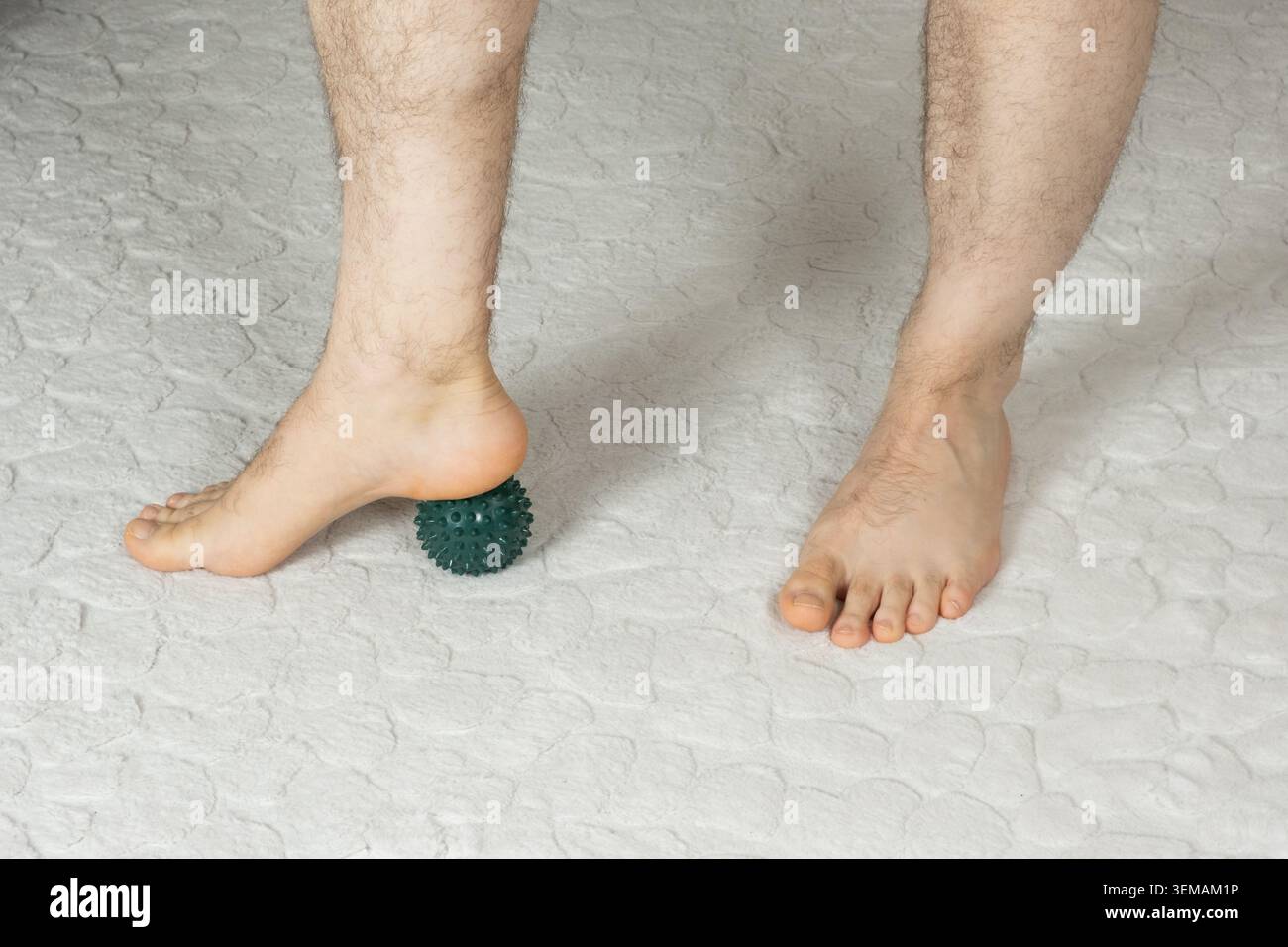 Mann massiert myofasziale Triggerpunkte am Fuß mit grünem Stachelballen Stockfoto