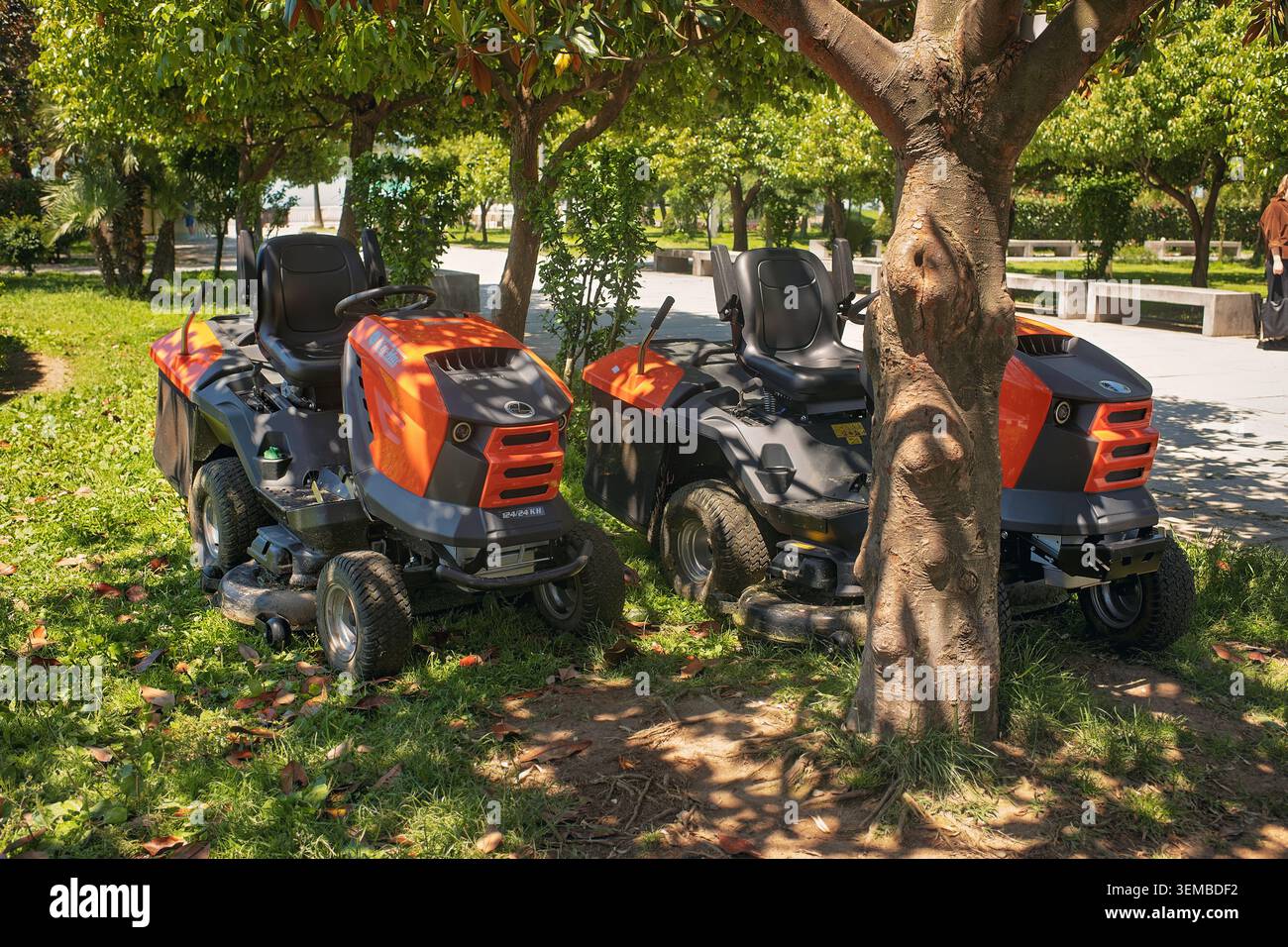 Batumi, Georgia - 3. Juni 2026: Zwei orangene Rasenmäher parken auf Gras in einem öffentlichen Park. Stockfoto
