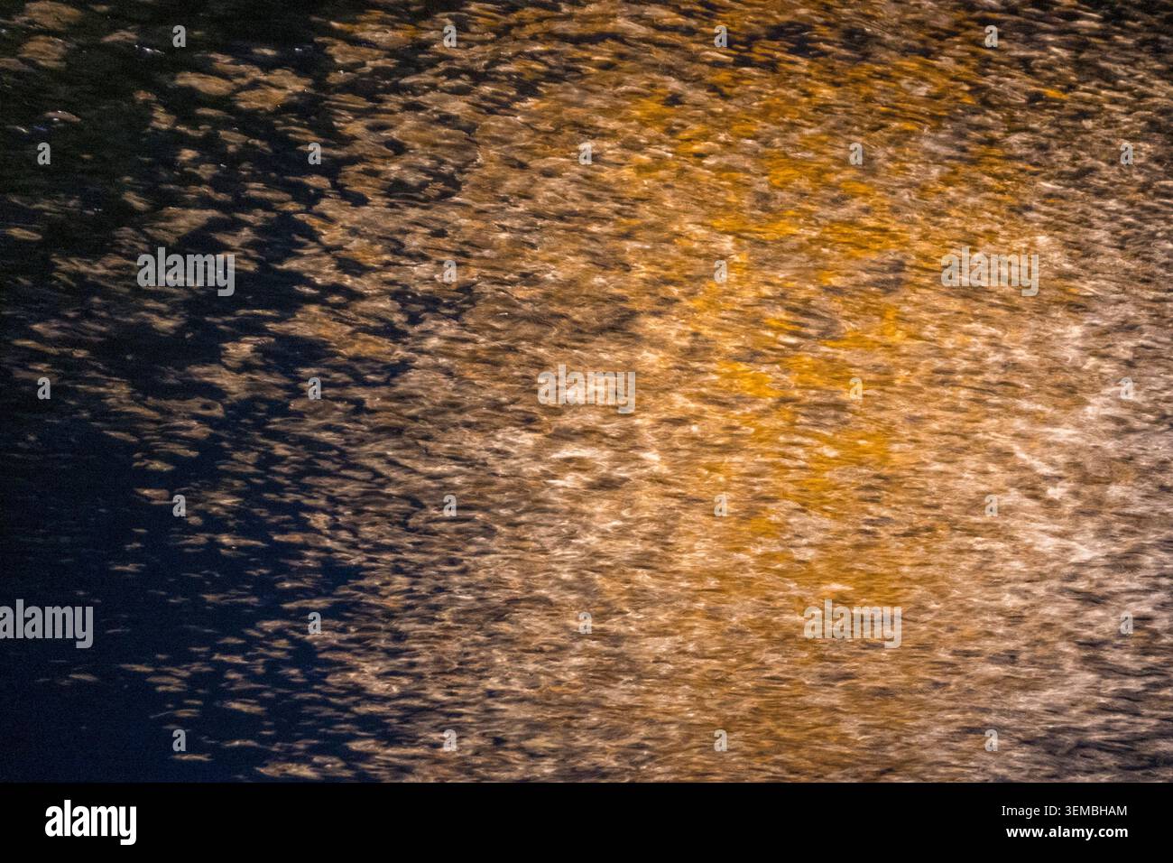 Abstrakte ICM-Aufnahme (Intent Camera Movement) mit goldenem Licht auf einer dunkelblauen Oberfläche, die eine fließende, energetische Textur mit Bewegungsunschärfe A erzeugt Stockfoto