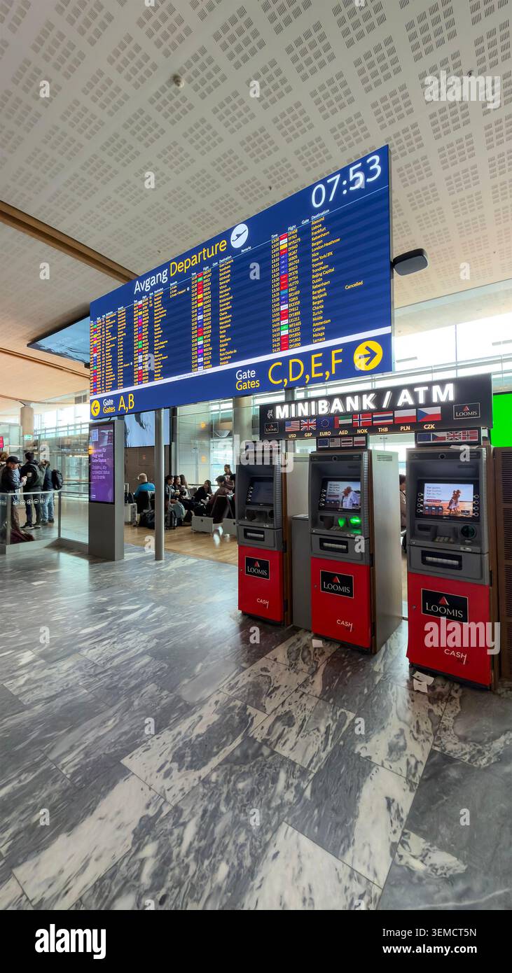 Loomis Geldautomaten befinden sich unter einem großen blauen Abfluginformationsbildschirm am Flughafen Oslo Gardermoen in Norwegen - Smartphone-aufgenommenes Stockfoto
