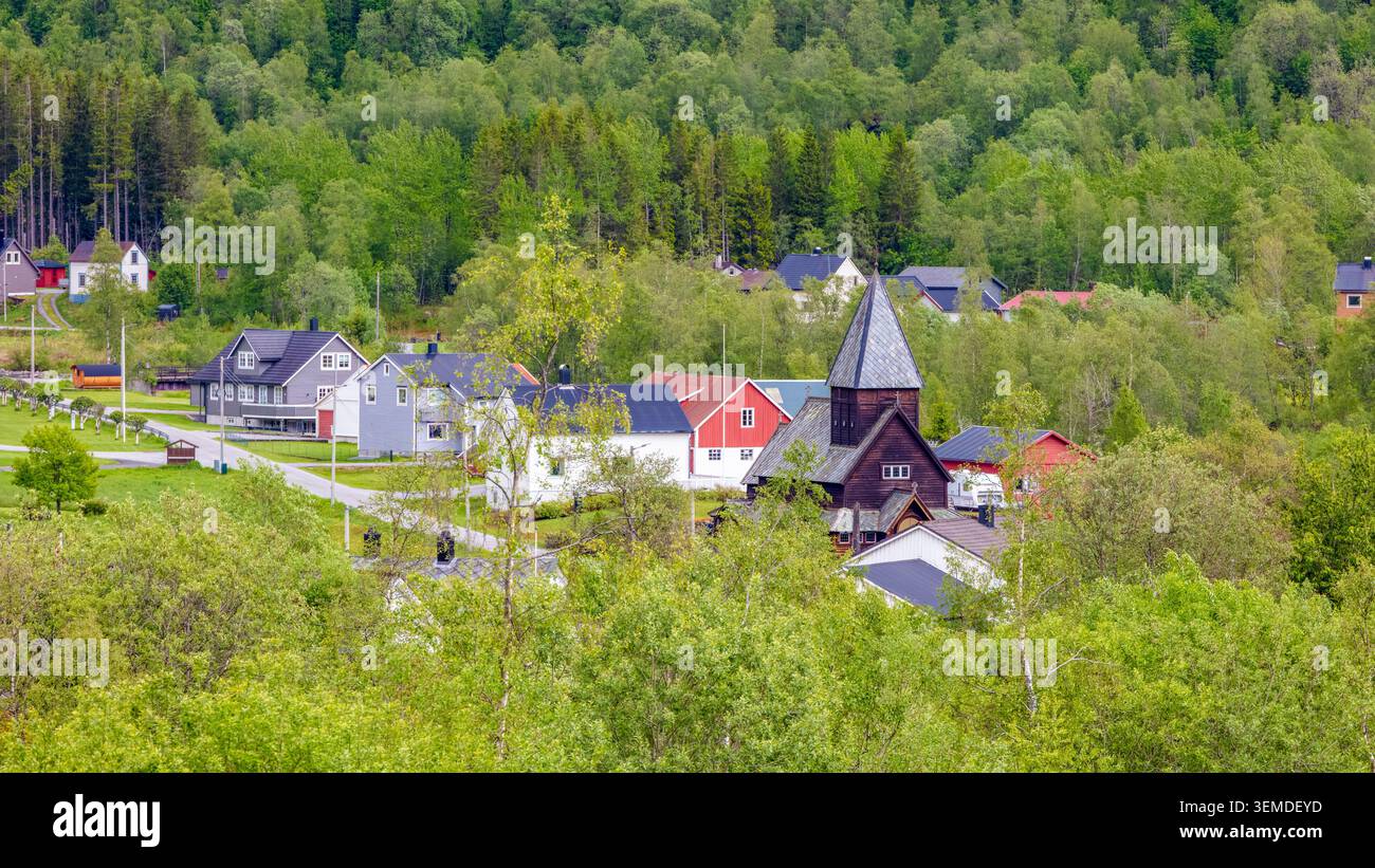 Nordisches Dorferbe mit traditioneller Holzkirche und farbenfrohen Häusern umgeben von üppigen Wäldern im ländlichen Norwegen für lokale Kultur und regionale Tu Stockfoto