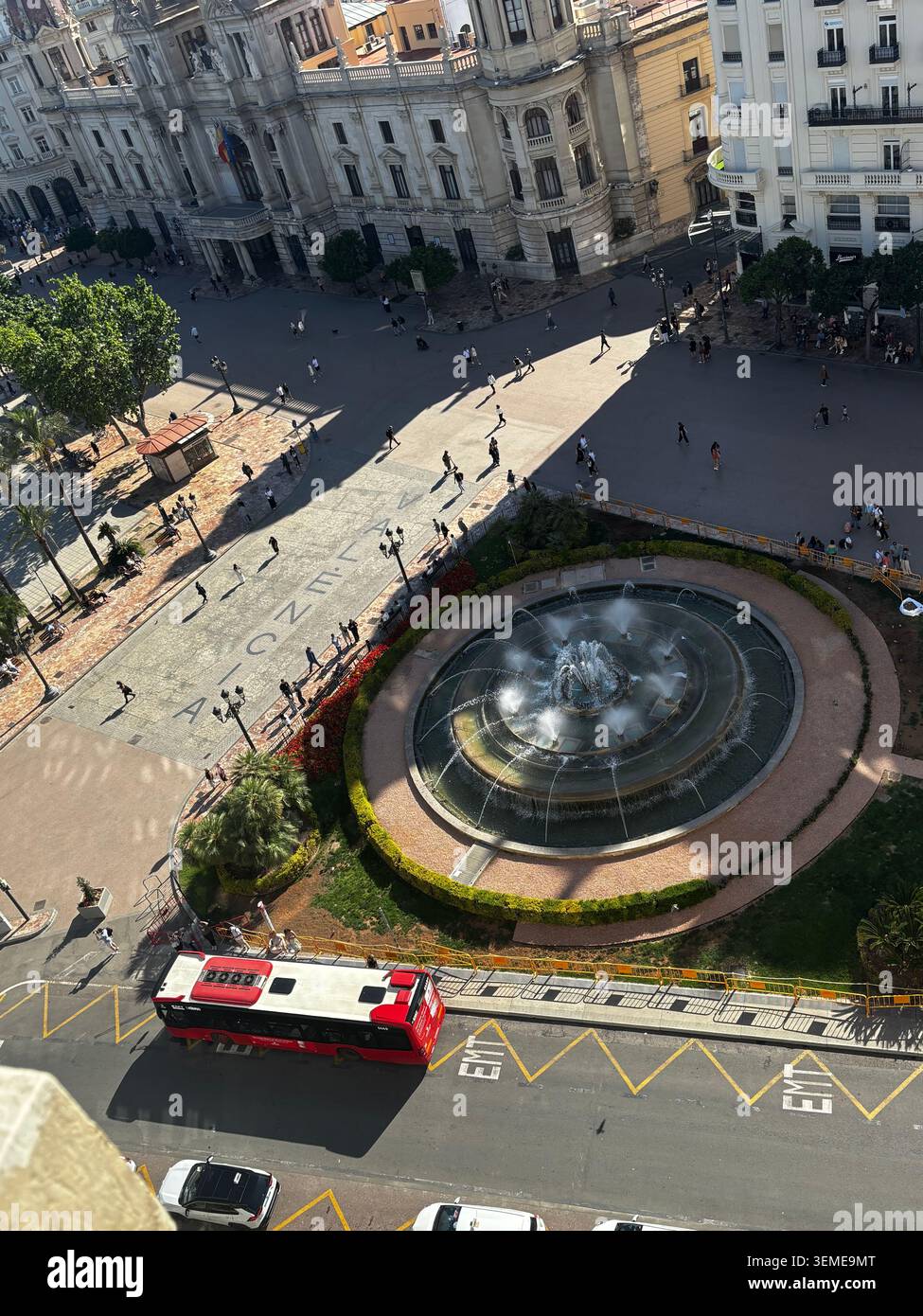 Erhöhter Blick auf die Plaza del Ayuntamiento in Valencia, Spanien, mit Brunnen, Fußgängern und einem roten Stadtbus. - Smartphone-aufgenommenes Stockfoto