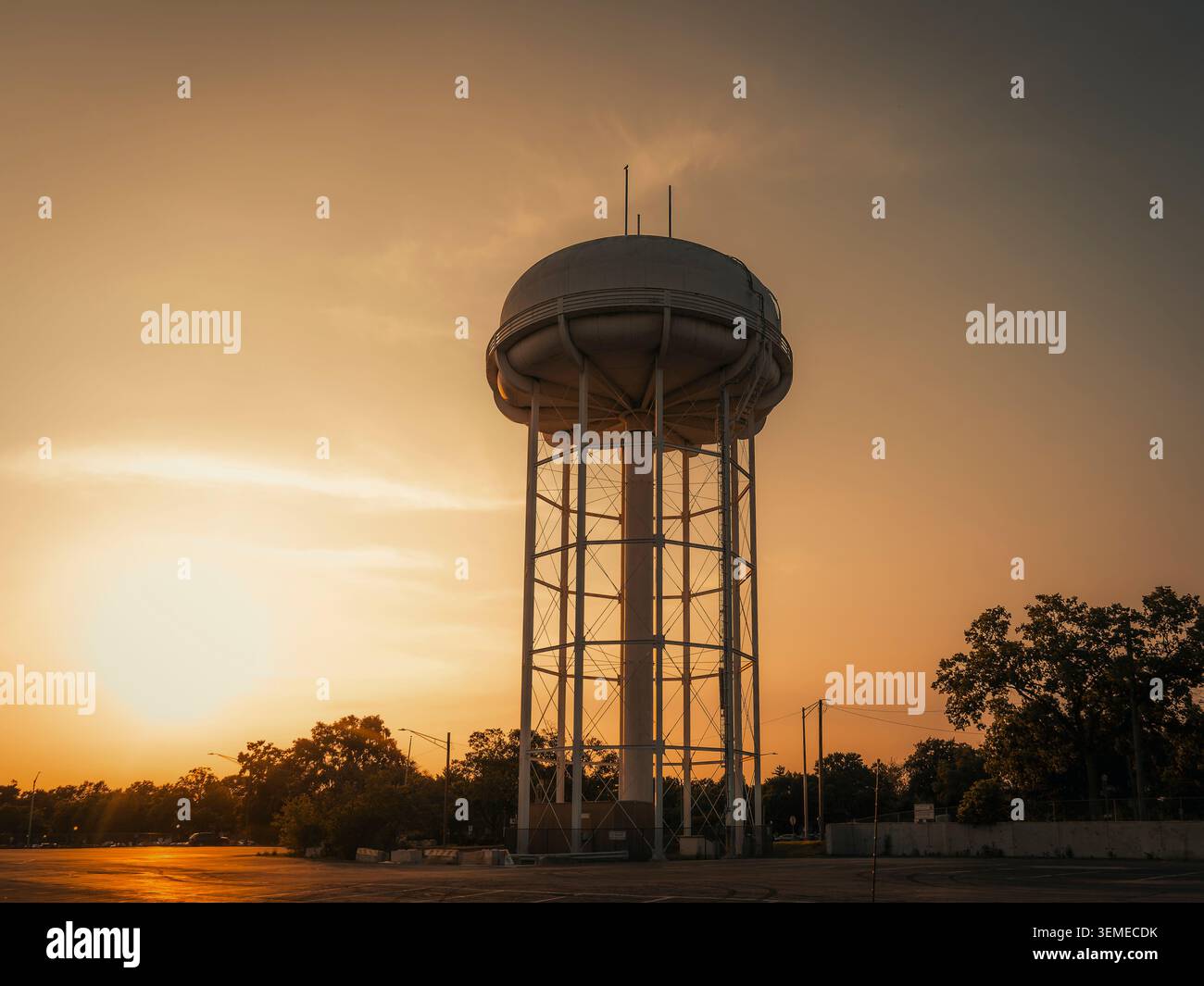 Städtischer Wasserturm aus Stahl, der in der Abenddämmerung in Naperville vor einem goldenen Sonnenuntergang steht Stockfoto