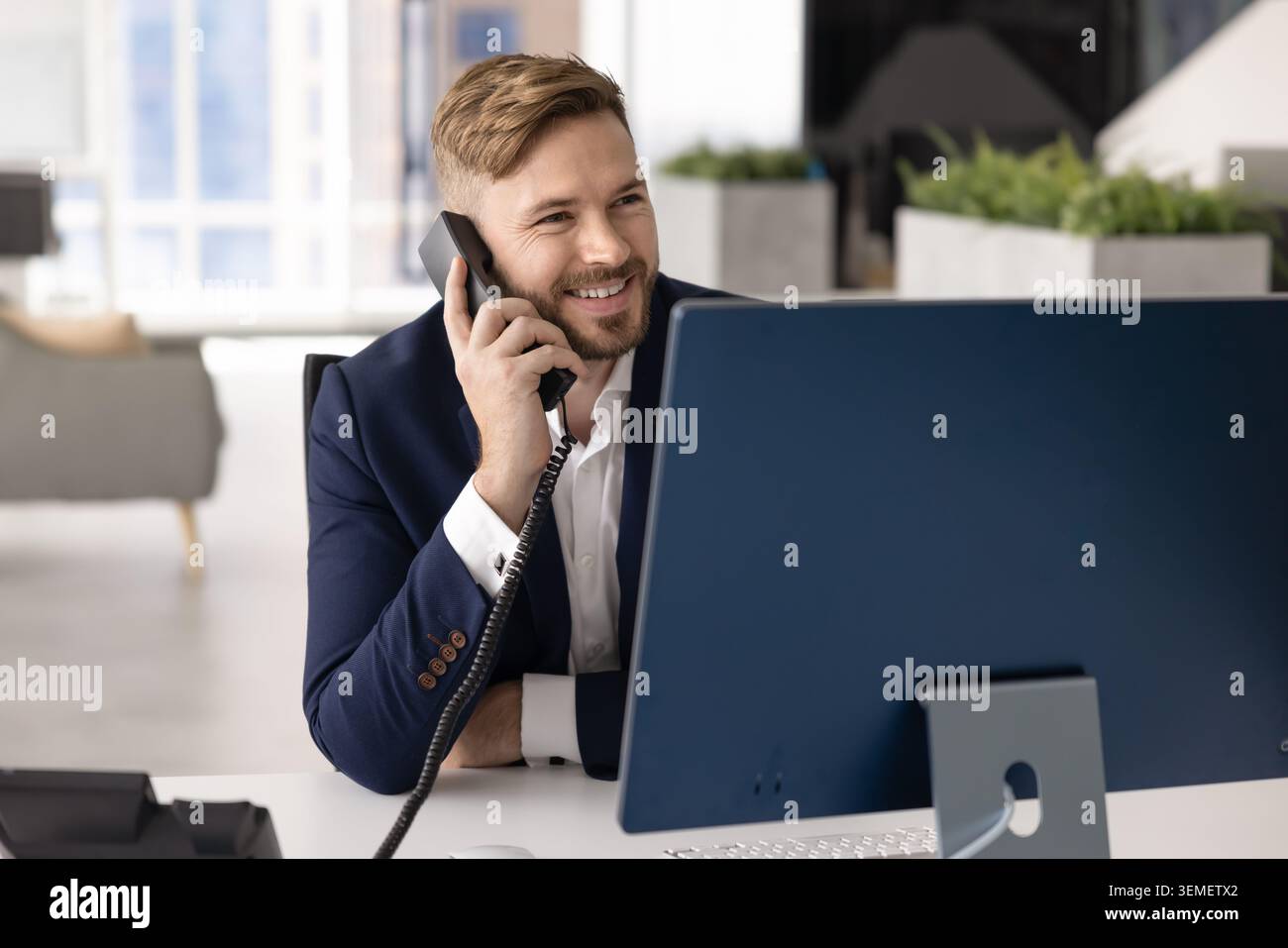 Lächelnder Geschäftsmann im Anzug, der im Festnetz telefoniert Stockfoto