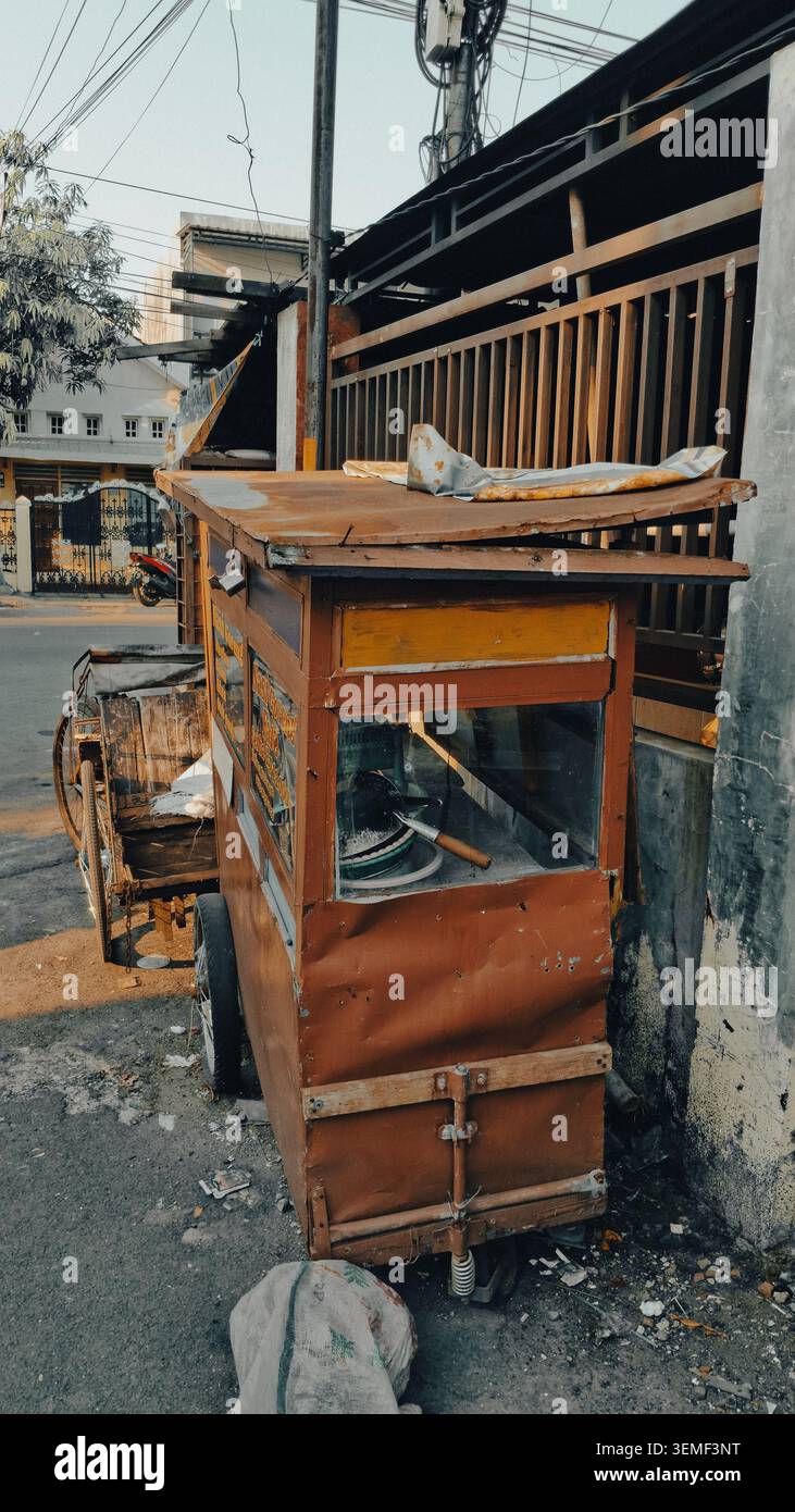 Ein alter mobiler Lebensmittelwagen mit verwitterter Holzkonstruktion und rostigen Metallteilen steht auf einem Bürgersteig. Stockfoto