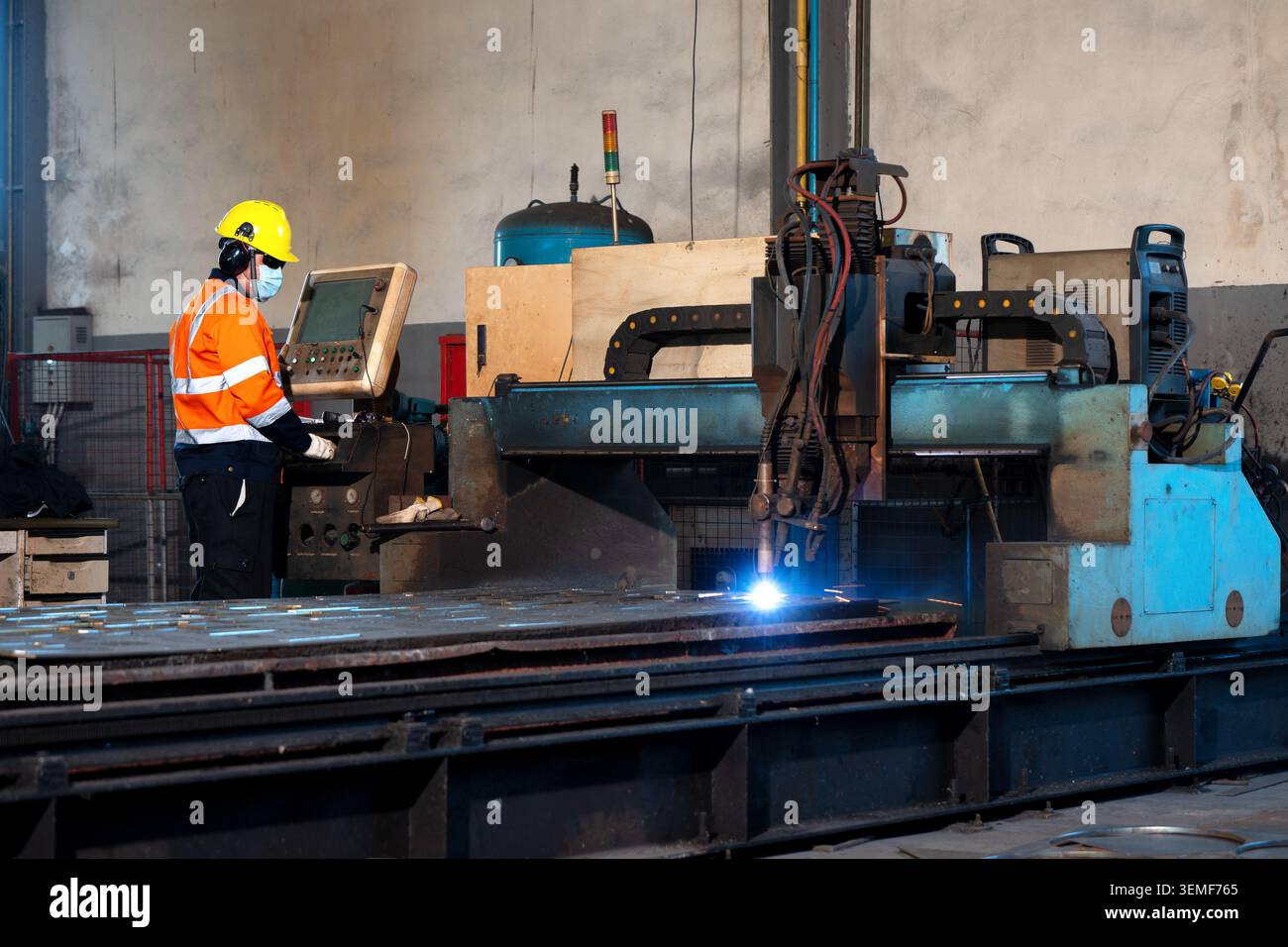 Industrielle Fabrikarbeiter, die automatisierte Laser-Metallschneider-Maschine bedienen, Ingenieur-Techniker-Bedienfeld automatisierte Laser-Metallschneider-Maschine schwer Stockfoto