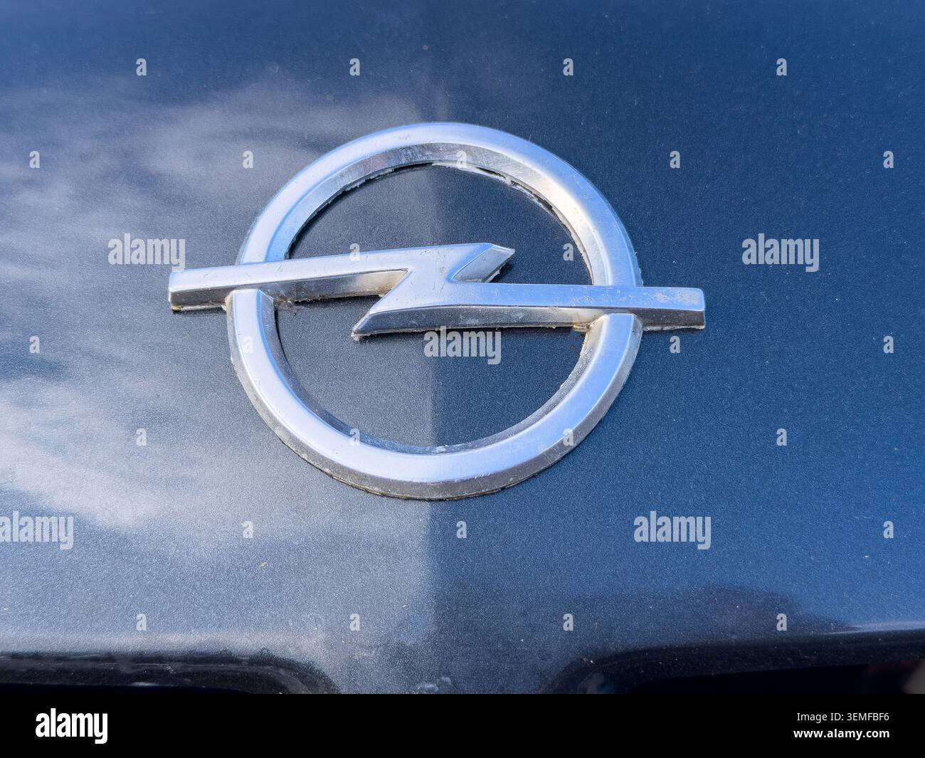 Nahaufnahme des silbernen Opel-Logoemblems auf einer dunklen Metallkarosserie - Smartphone-aufgenommenes Stockfoto