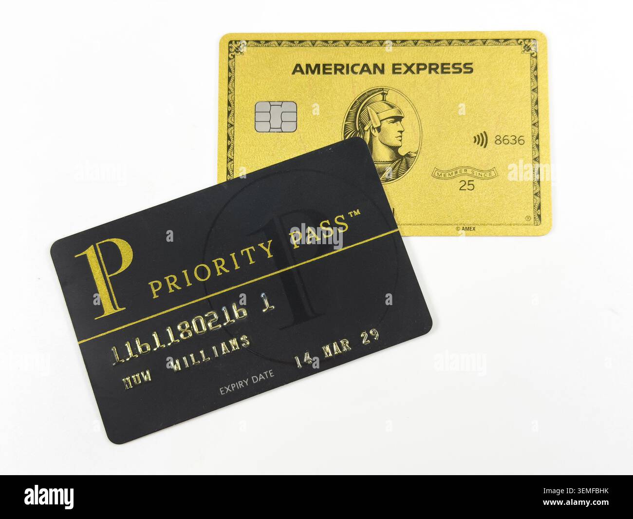 Eine American Express Gold-Kreditkarte neben einer schwarzen Priority Pass-Mitgliedskarte auf weißem Hintergrund - Smartphone-aufgenommenes Stockfoto