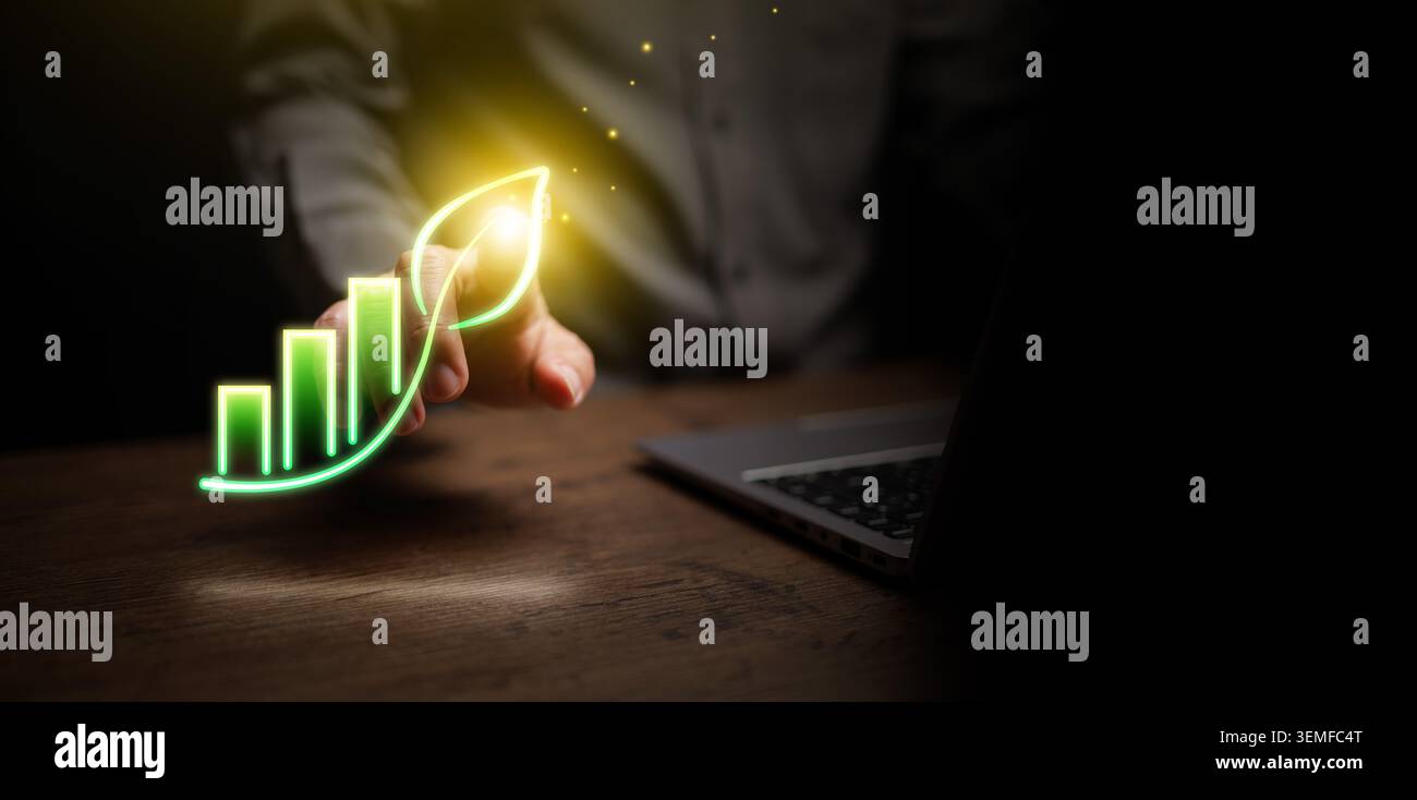 Business Professional mit leuchtend grünem Wachstumskarte, das als Blatt neben dem Laptop geformt ist. ESG-Strategie, nachhaltiges Wachstum, grüne Innovation, digitale Transformation Stockfoto
