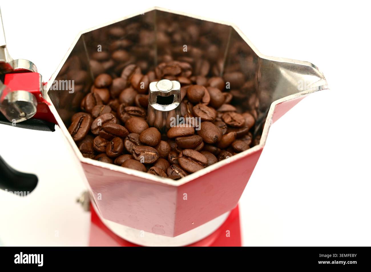 Nahaufnahme gerösteter Kaffeebohnen in einer roten Mokakanne (Espresso) auf weißem Hintergrund. Stockfoto