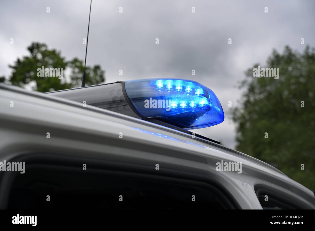 Blinkender blauer Lichtbalken an einem deutschen Polizeiauto vor dunklem bewölktem Himmel, Warnsignal während einer Operation zum Schutz der Öffentlichkeit, Kopierraum, ausgewählter Fokus Stockfoto