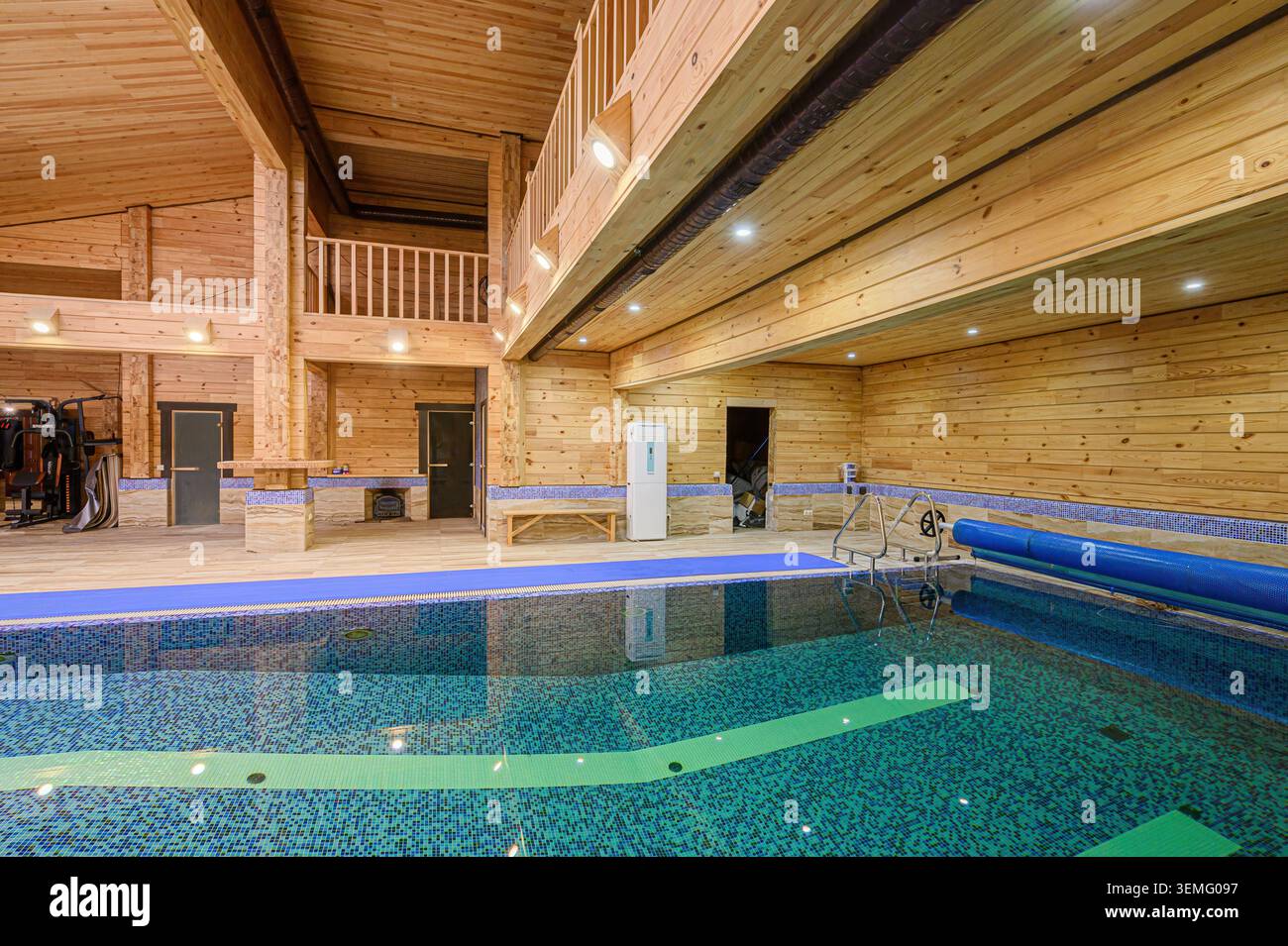 Innenpool mit Holzvertäfelung, Fitnessgeräten und Zwischengeschoss. Stockfoto