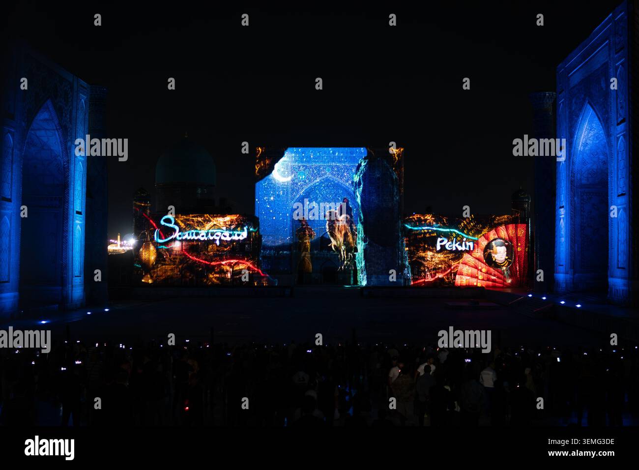 September 2026. Samarkand Usbekistan. Touristen laufen abends auf dem Registan-Platz in Samarkand, Usbekistan. Beleuchtete Madrasen. Gruppen Stockfoto